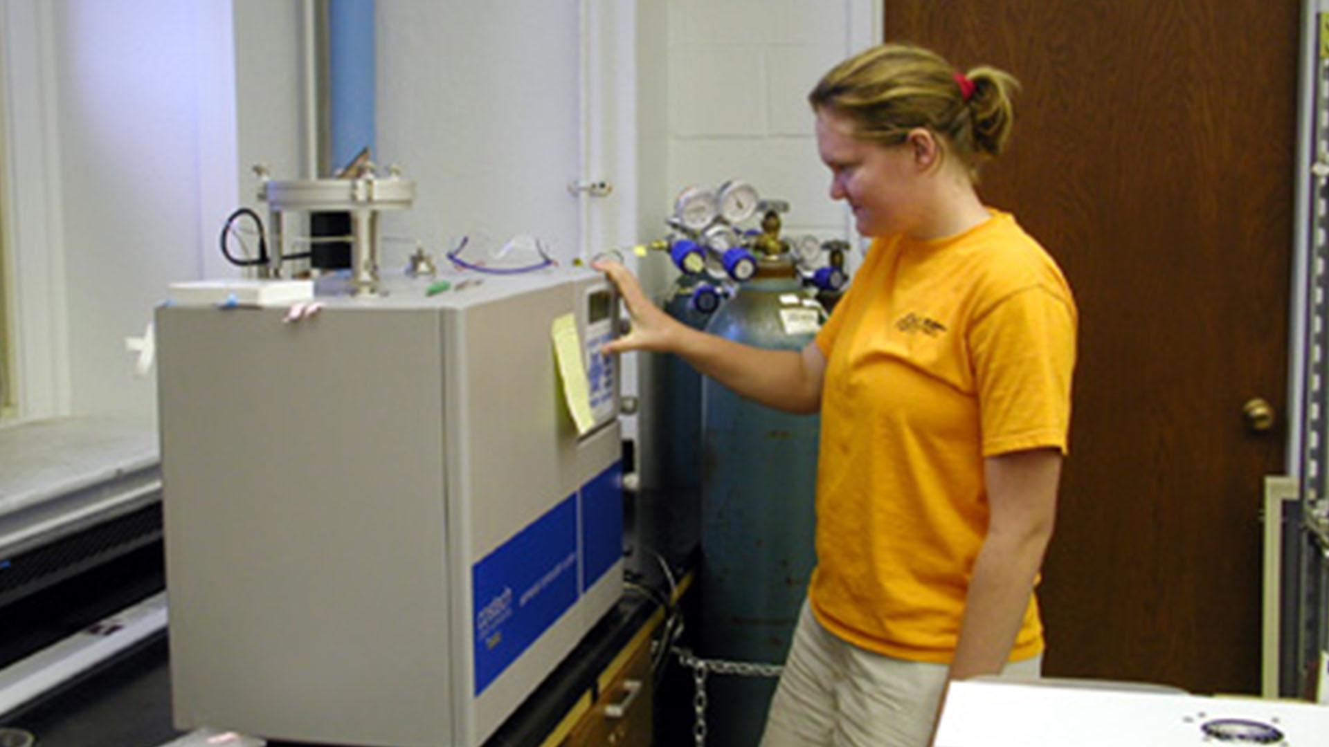 Student using stable isotope mass spectrometer in lab.