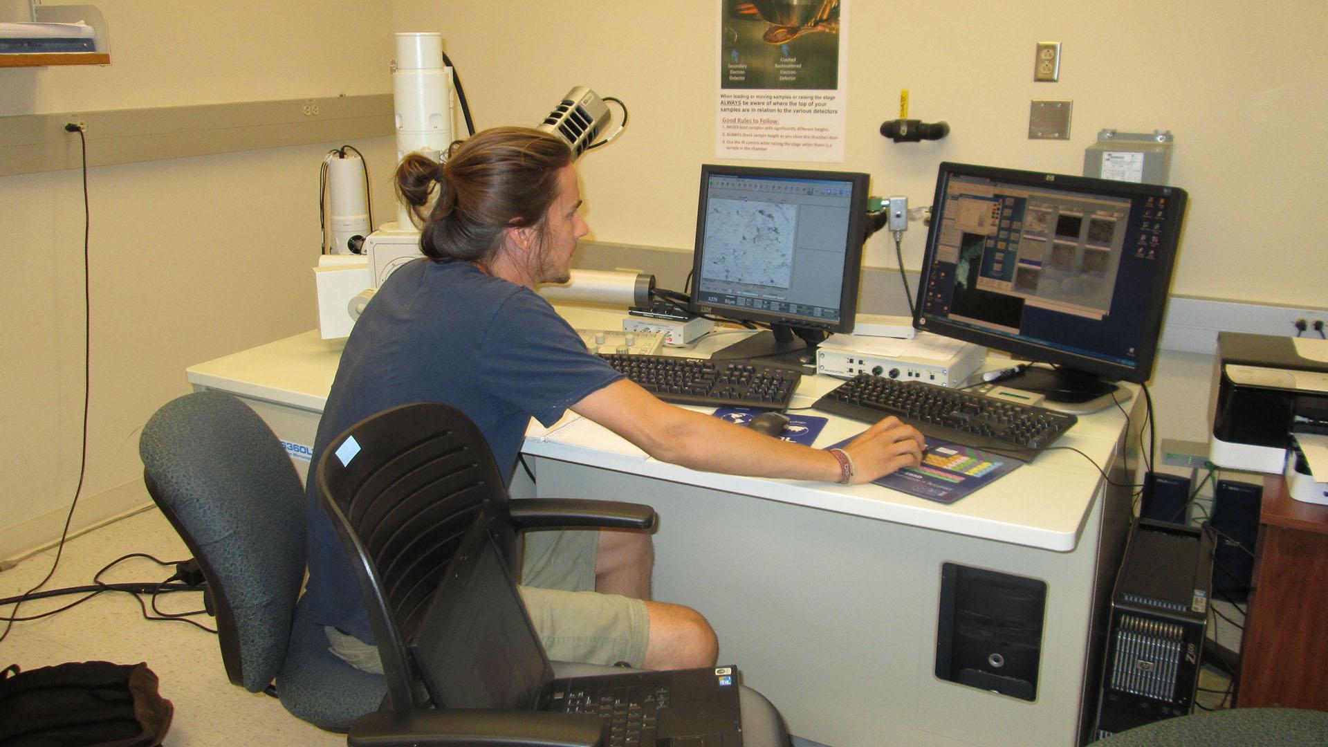 Student using electron microscope in lab.