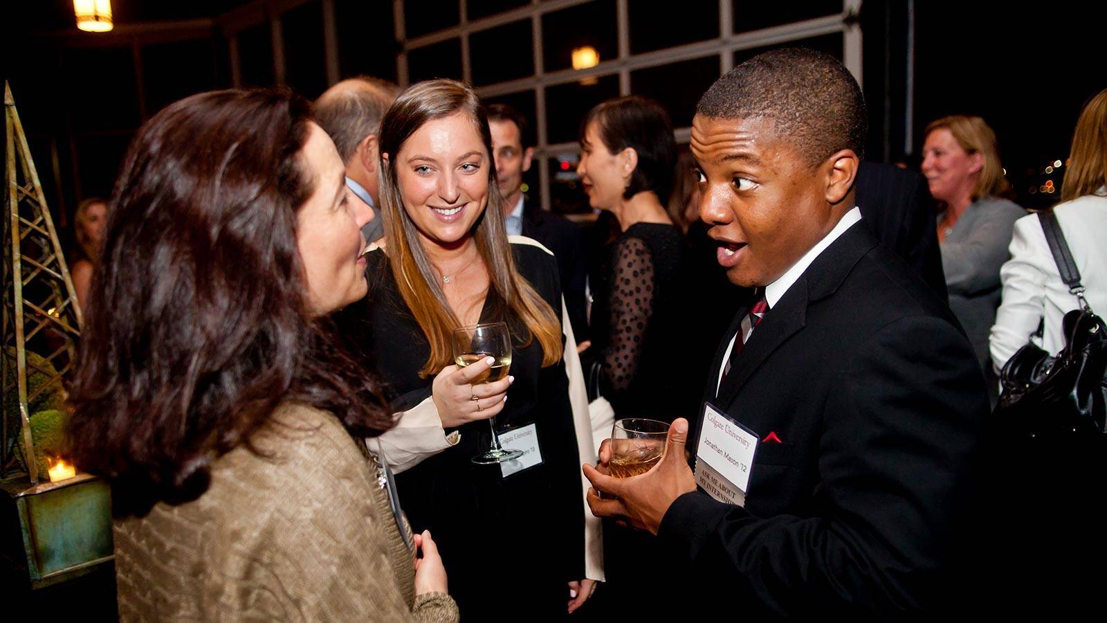 Alumni converse over drinks at an off-campus Colgate event.=