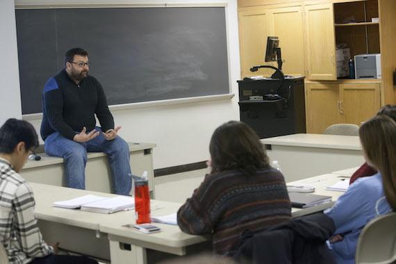 Jason Keith sits on a table in a classroom in Olin Hall.