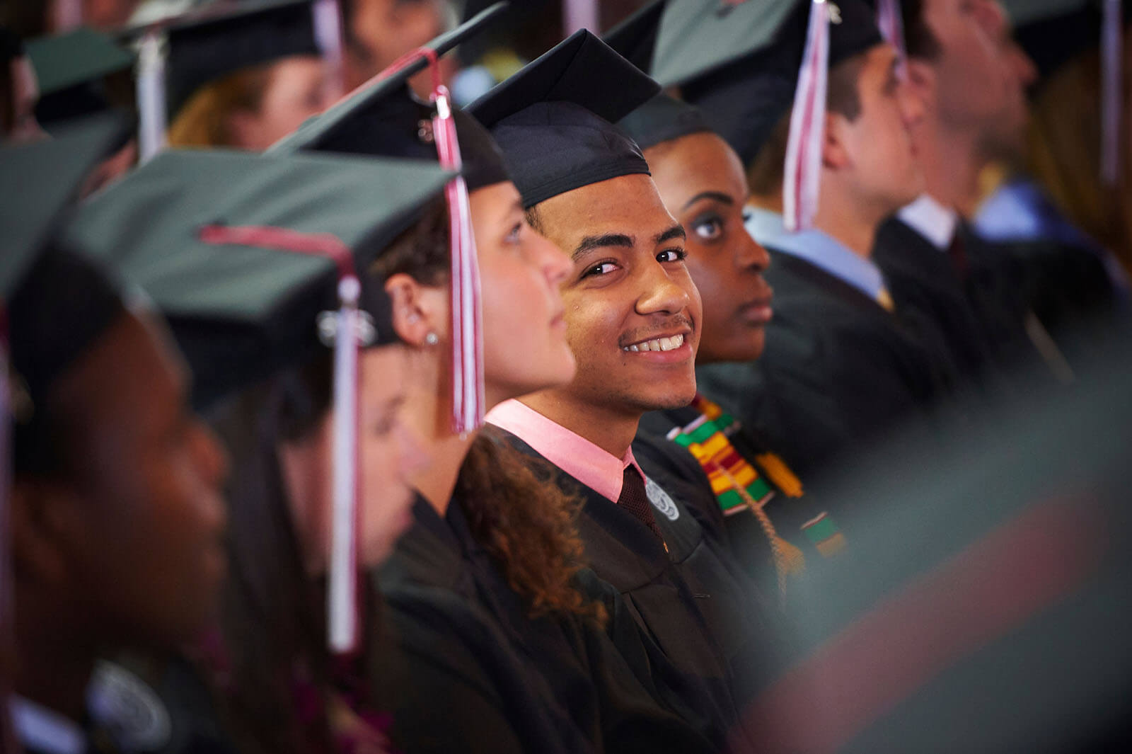 Student in cap and gown smiles cheekily at the camera