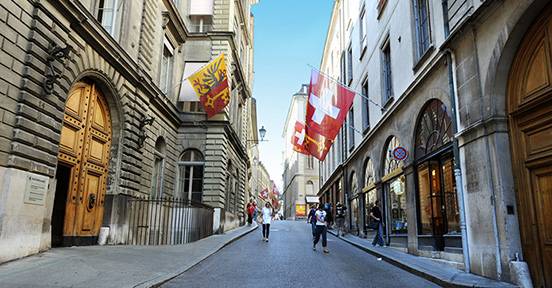 Street view of Geneva with flags and people walking.