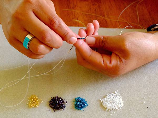 Close-up of hands performing beadwork