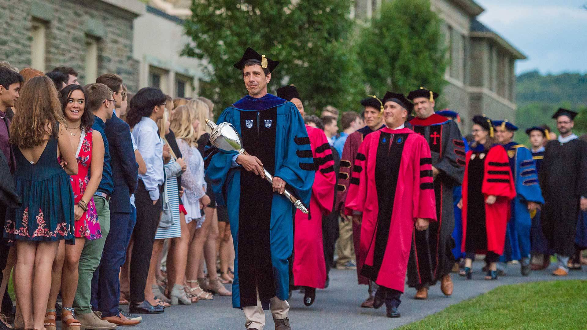 Faculty members in academic regalia process past the first-year class as part of the Founders' Day Convocation procession