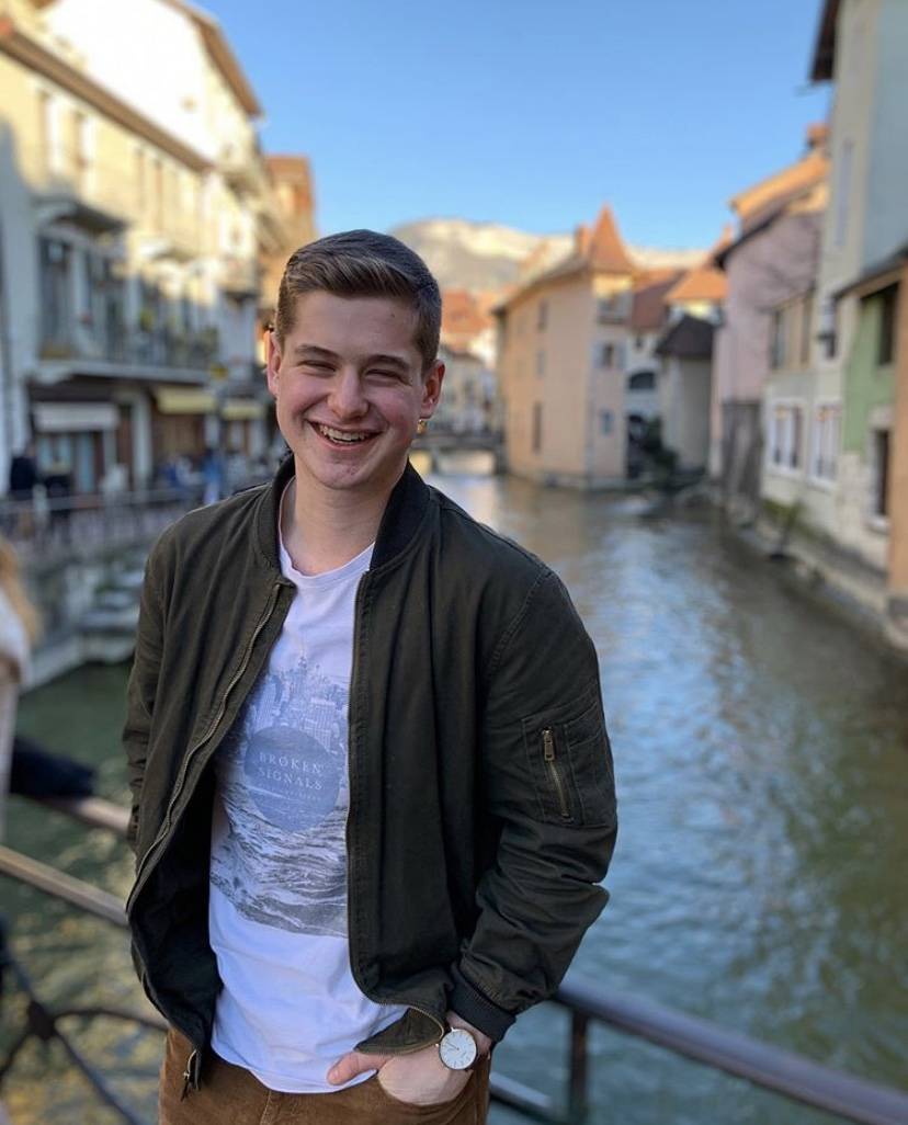 A picture of Cole on a bridge overlooking a stream.