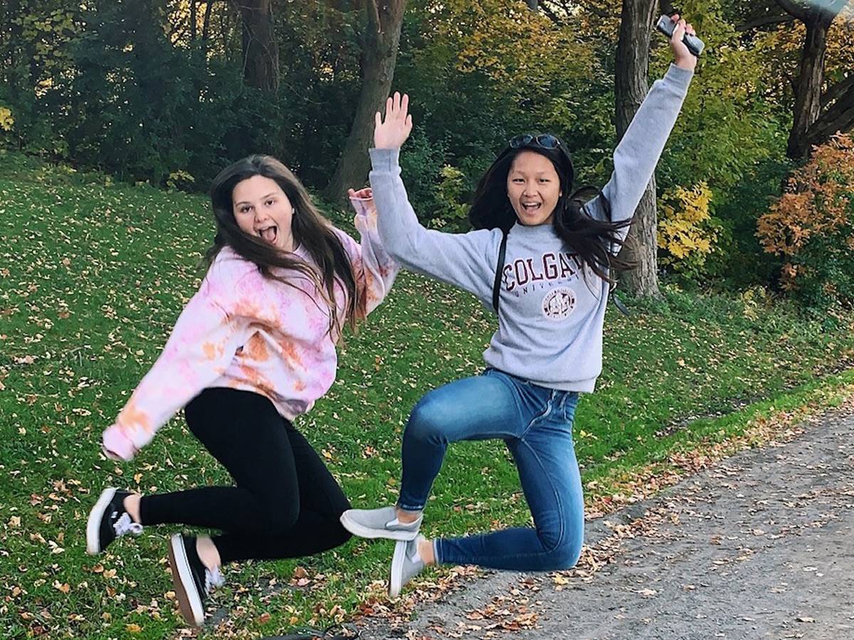 Eliza and her friend jumping outside.