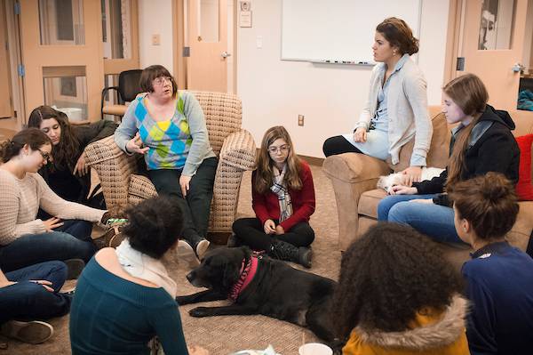 Group gathers in a circle around therapy dog