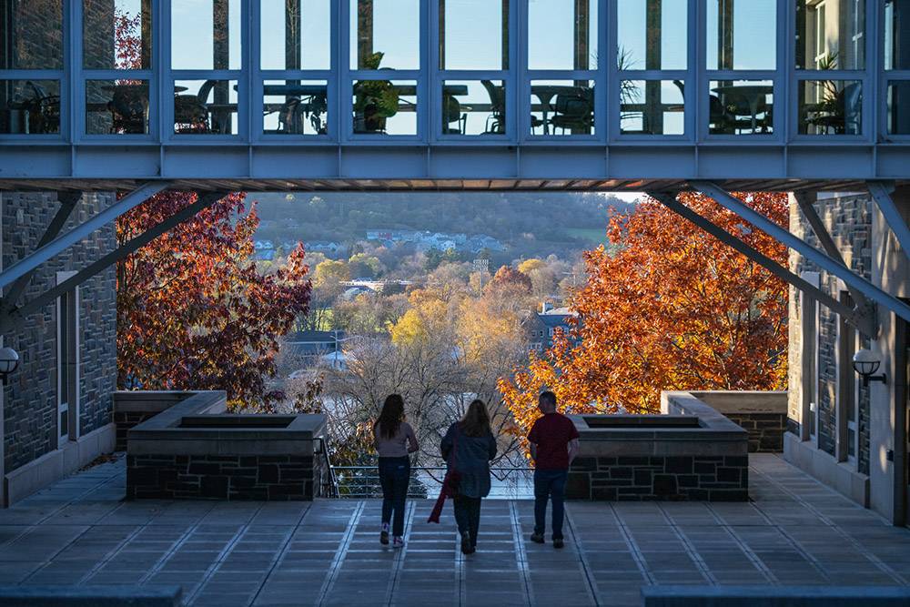 Three students walk under the Persson Hall bridge