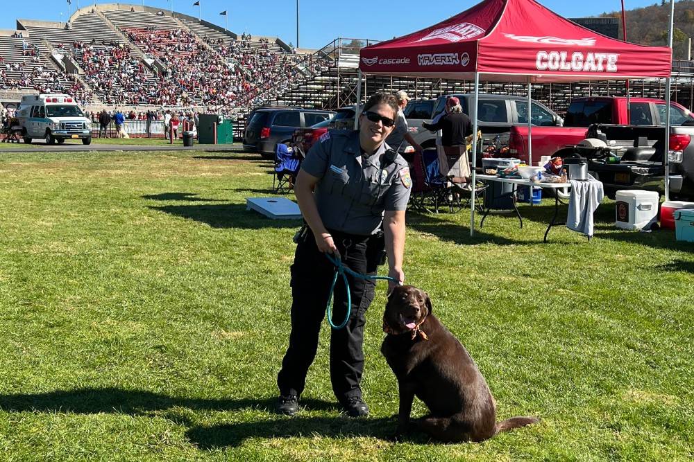 Campus safety officer with a dog on the football field