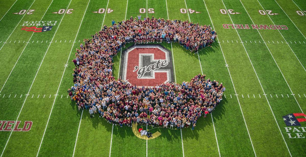 People stand in the shape of a C on football field