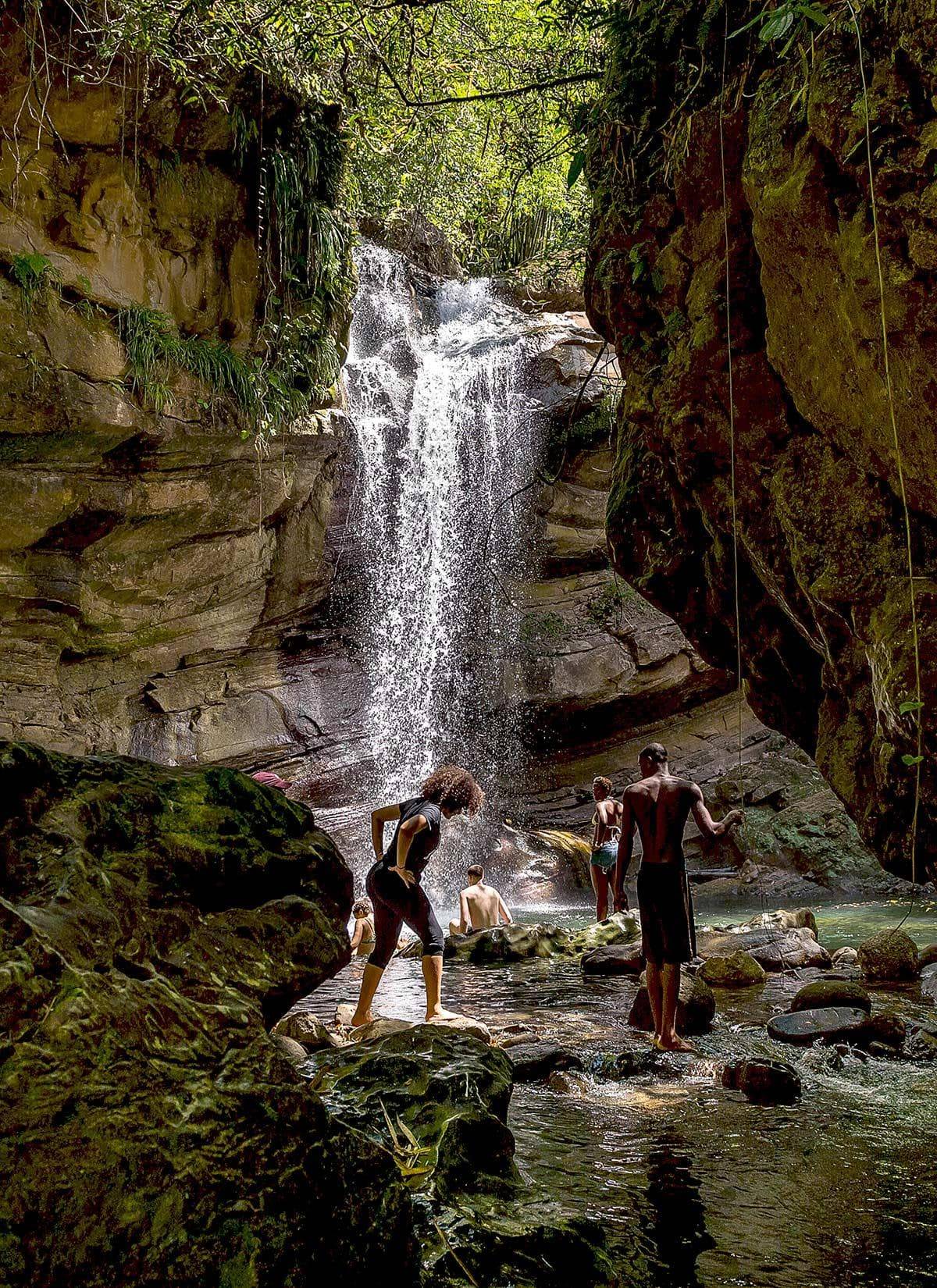 Students walking and swimming near a Jamaican waterfall