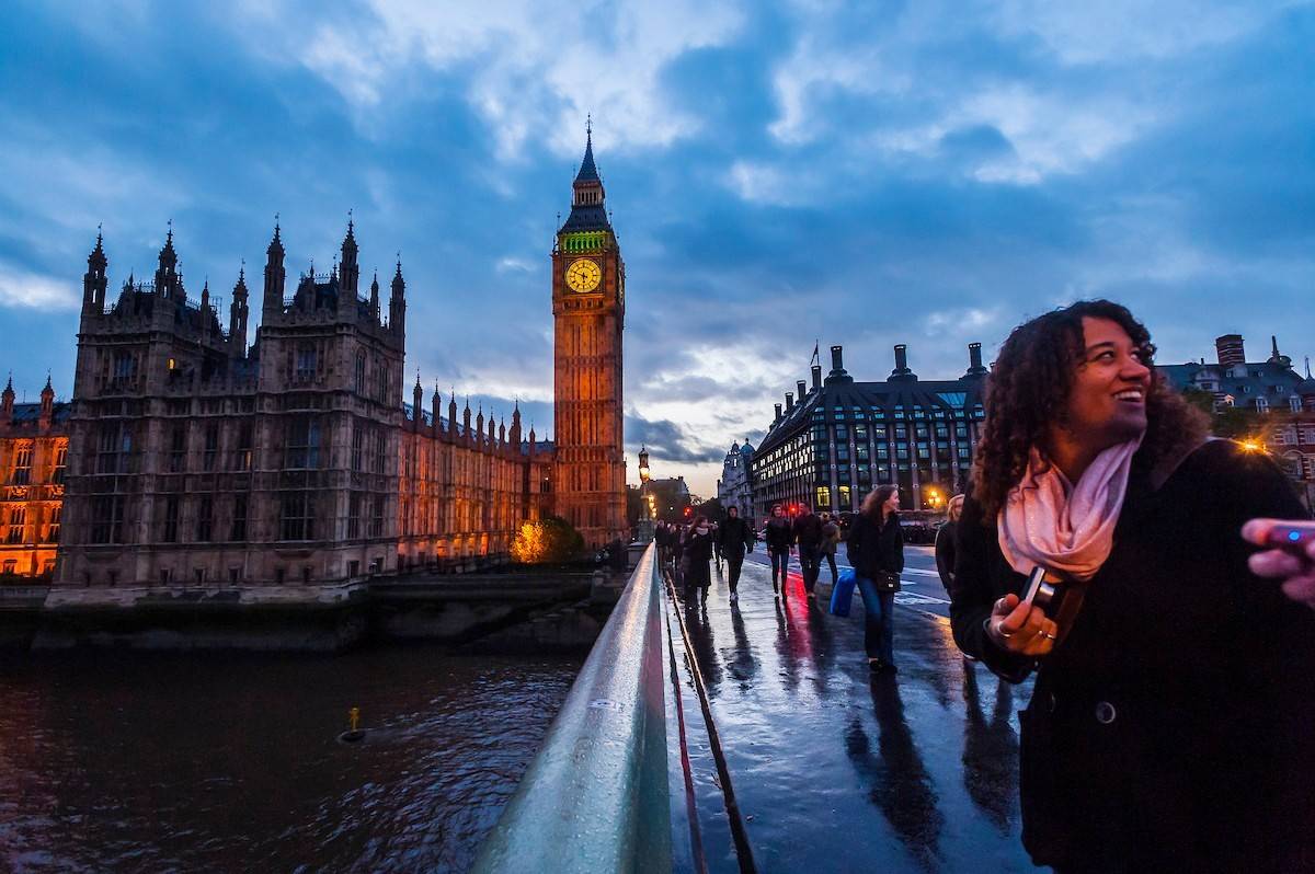 A student poses on a bridge near Big Ben in London