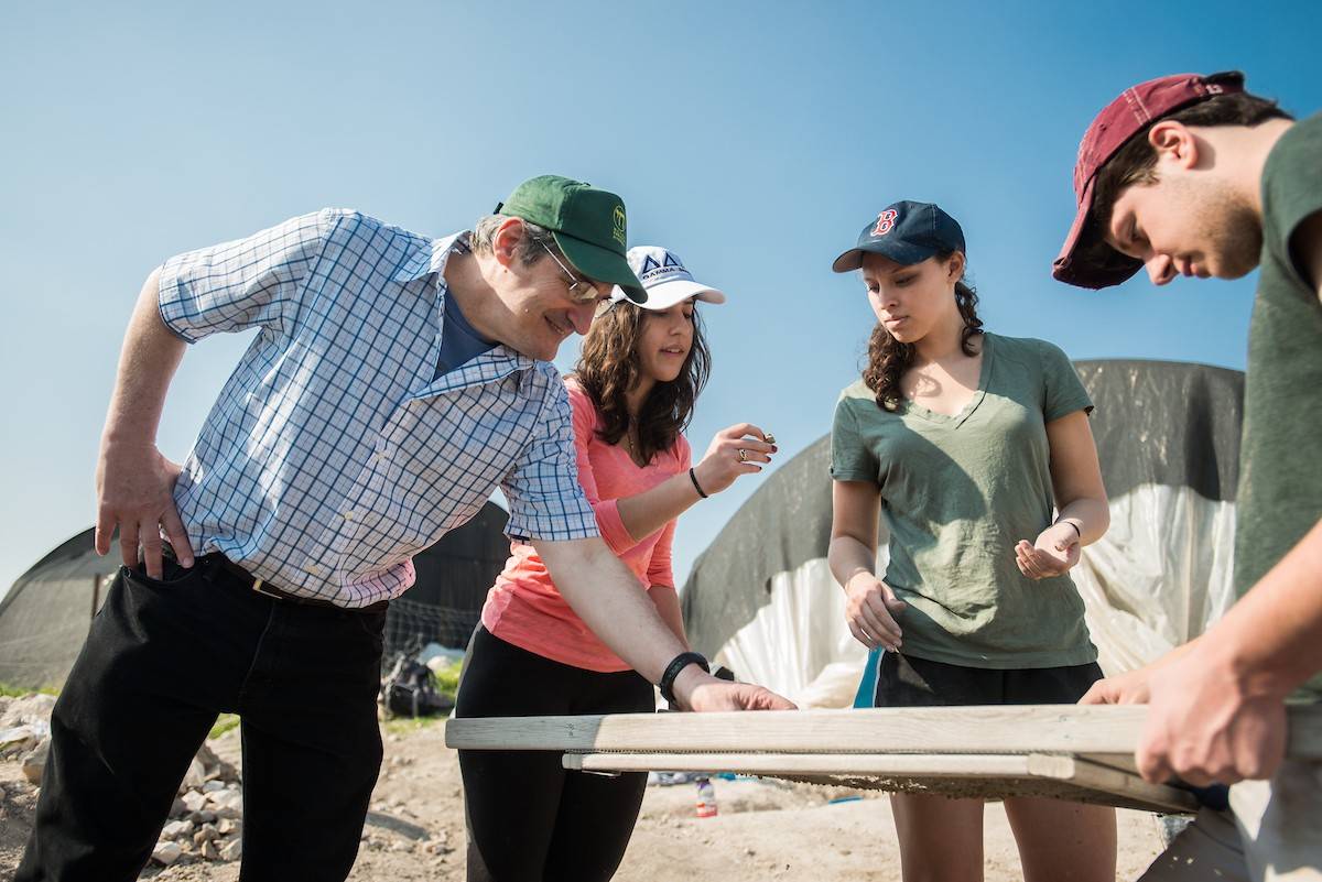 Students and a professor sift through sand