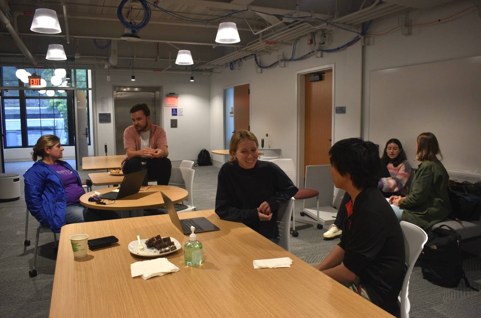 man sitting on table with other people around him talking 