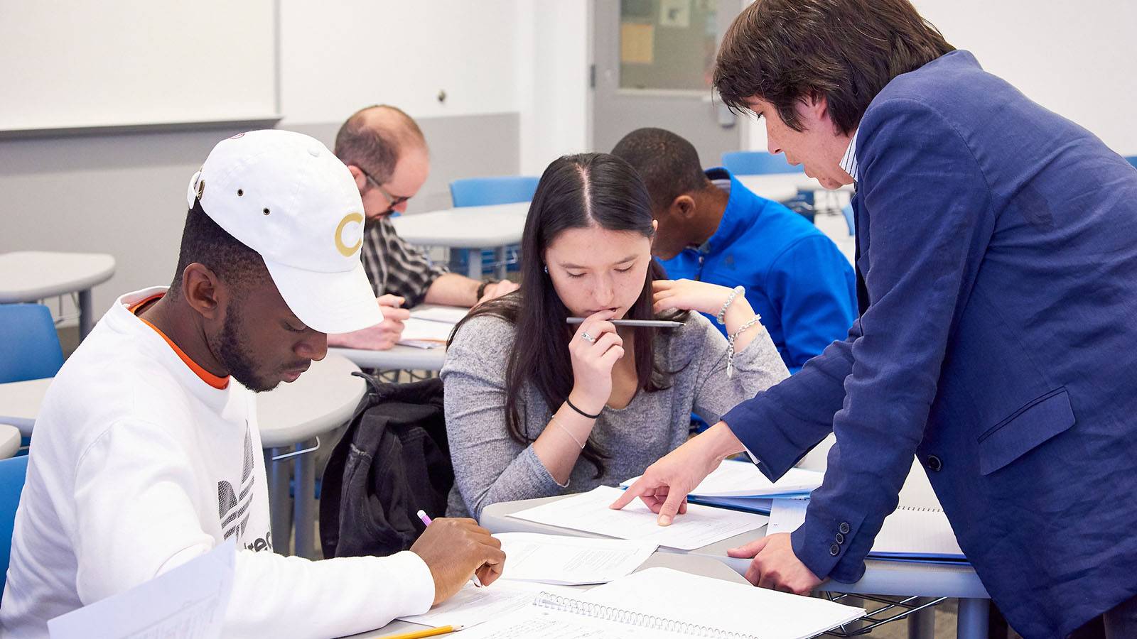 A faculty member helps two students in class