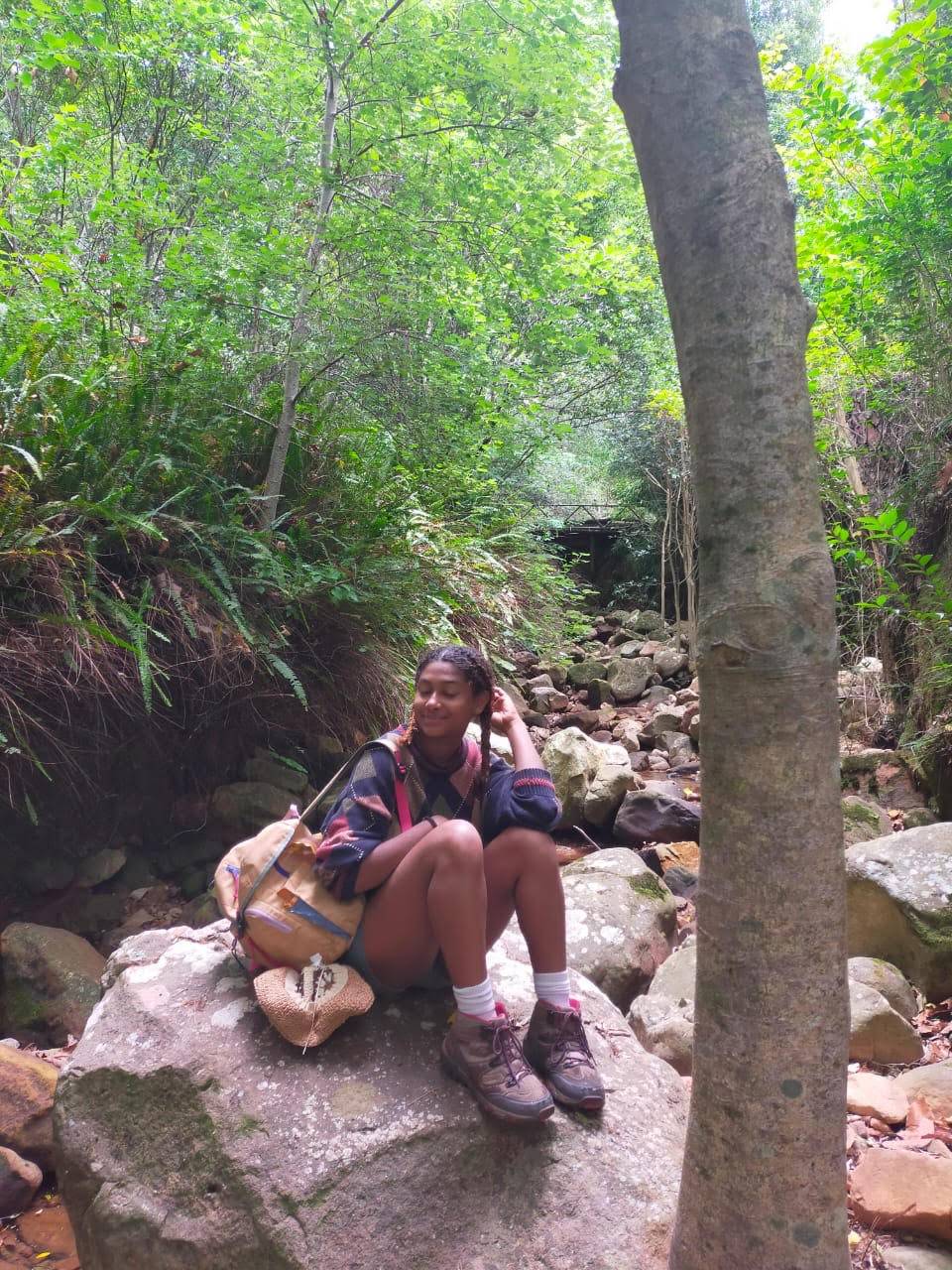 Photo of Sarafina sitting on a rock in the forest.