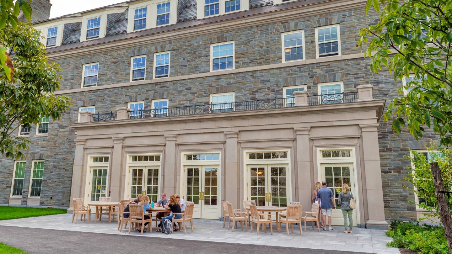 Spring photo of campus with students sitting outside on a patio