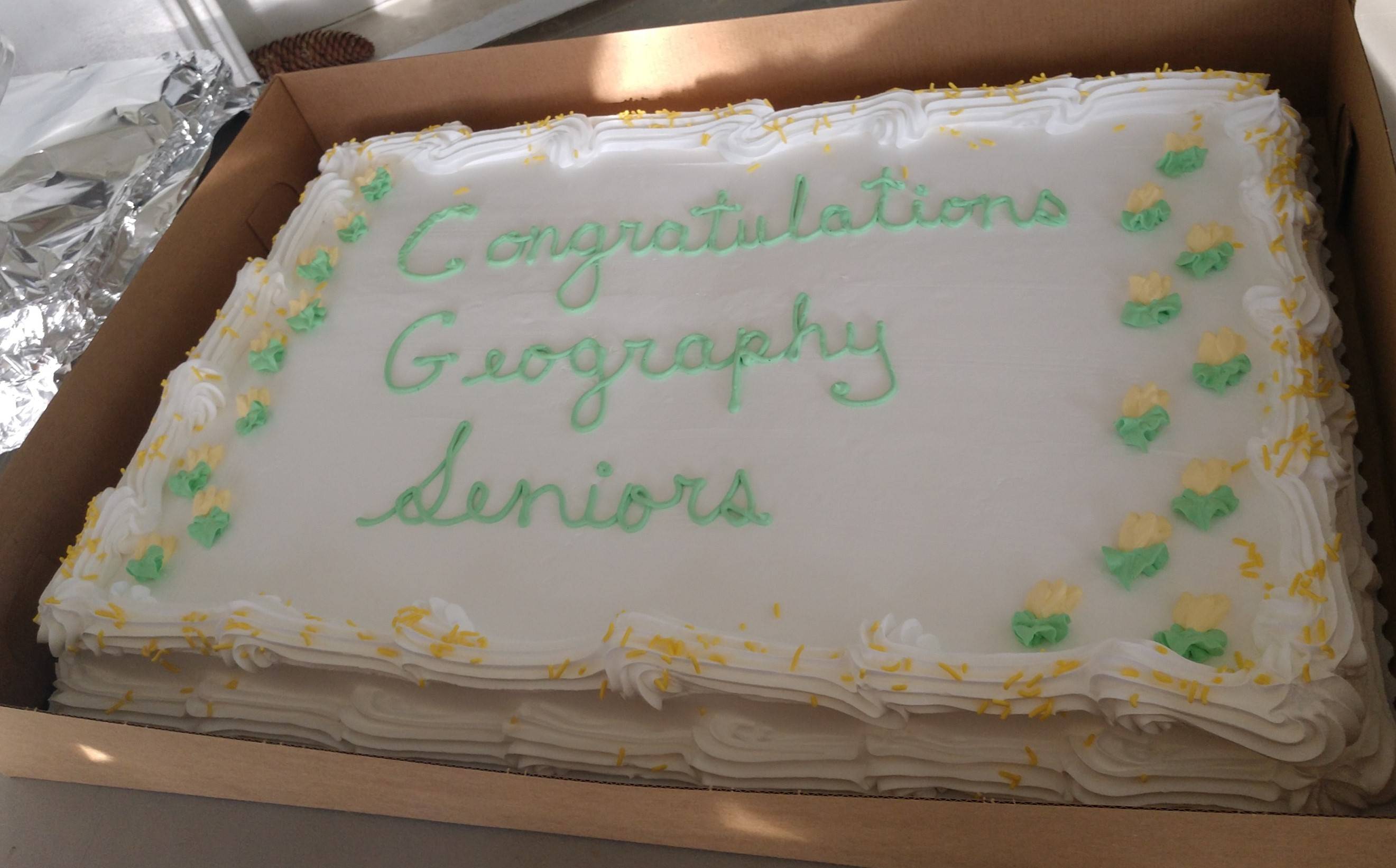 Image of white and green cake, text reading "Congratulations Geography Seniors."