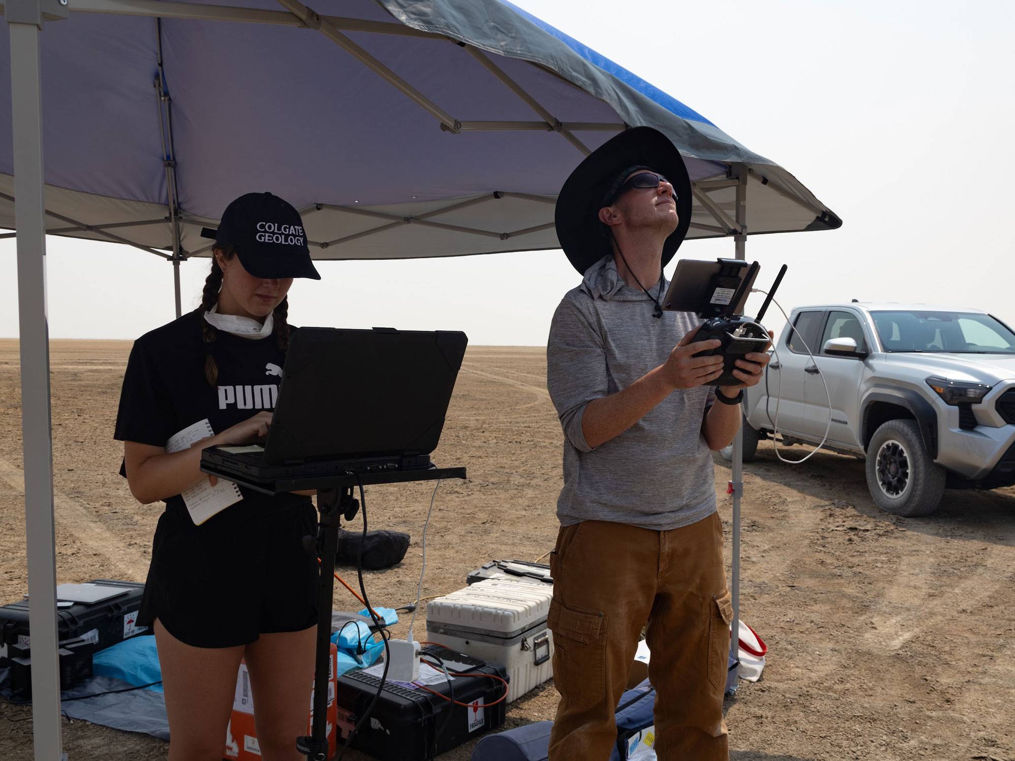 Joe Levy and student fly drone while standing under tent