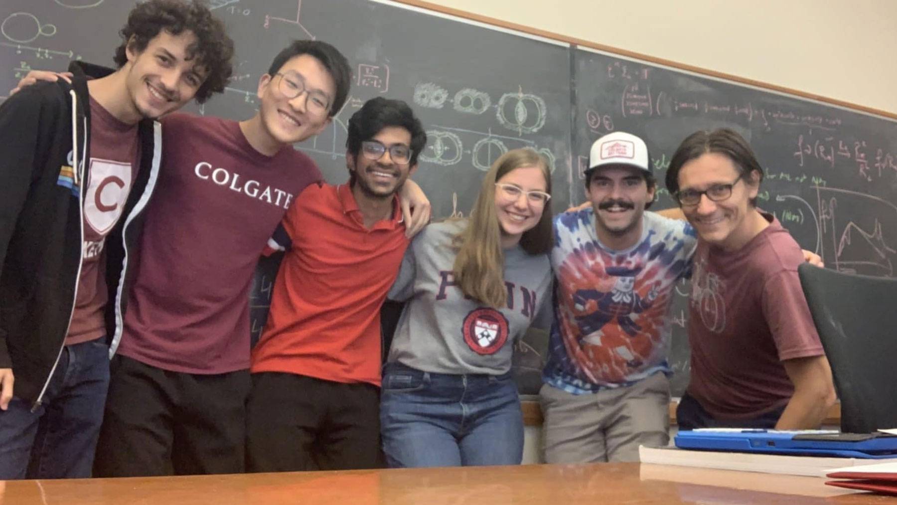 Researchers gather in front of chalkboard 