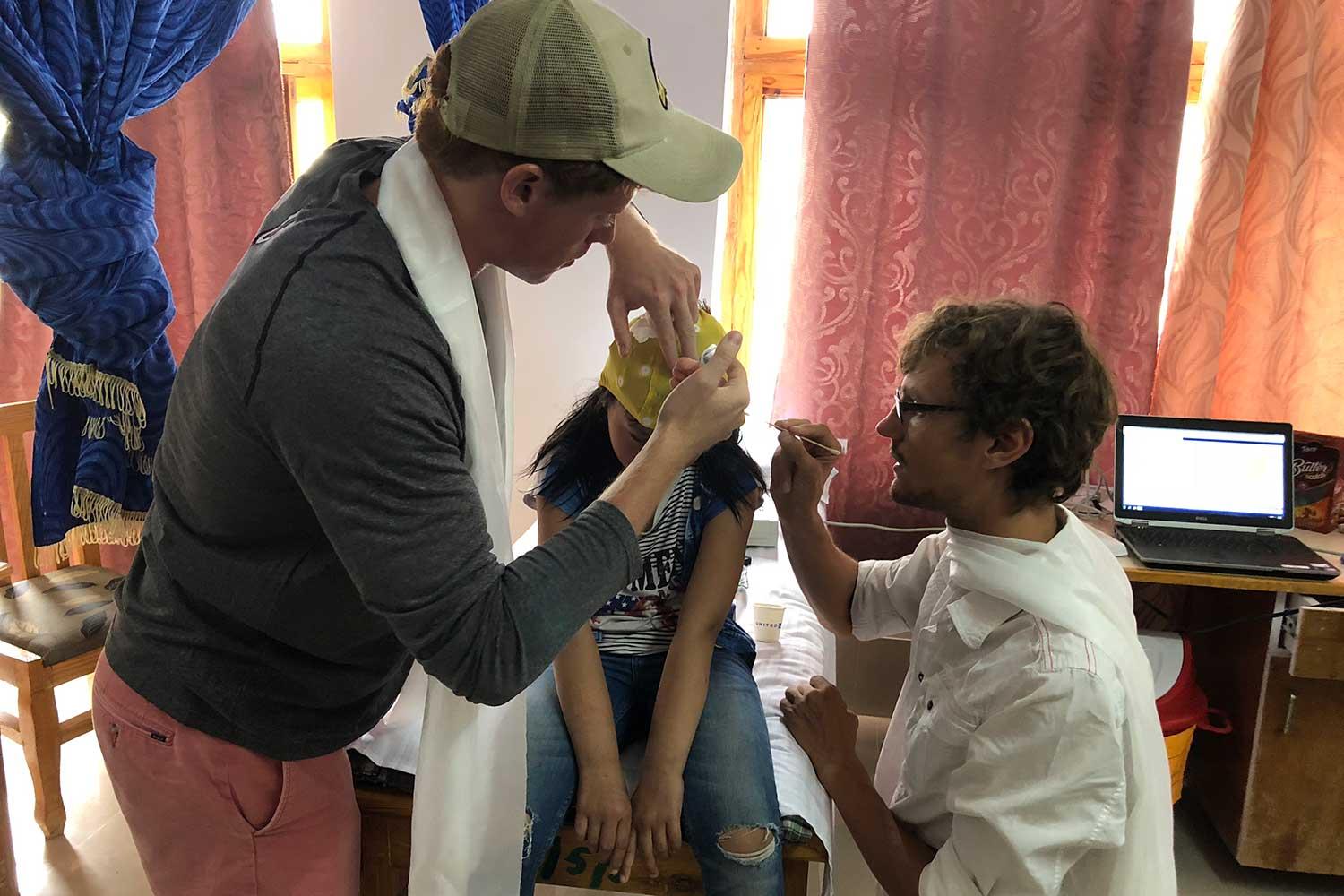 Patrick Needham ’20 and a physician work with a pediatric neurology patient applying a cap that will allow them to run tests